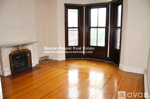 A room with a fireplace and wooden floors is on the market with Boston Proper Real Estate.