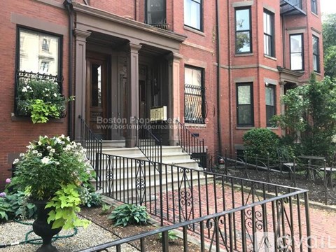 A red brick building with a black iron fence in front.