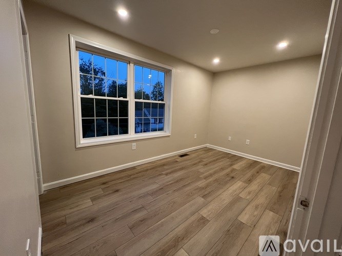 A room with a large window and wooden flooring.