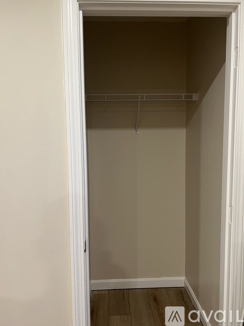 A white doorway leads to a room with a wooden floor and a wall.