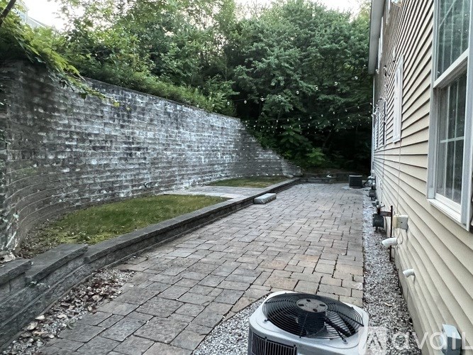 A wall of bricks and a fan on a patio.