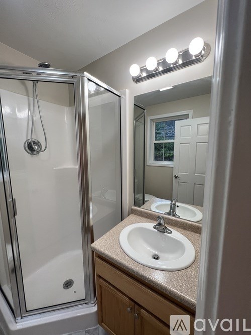 A bathroom with a sink, mirror, and shower.