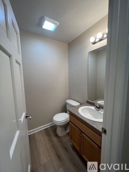 A bathroom with a toilet, sink, and mirror.