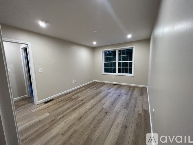 A room with wooden flooring and a window with bars on it.
