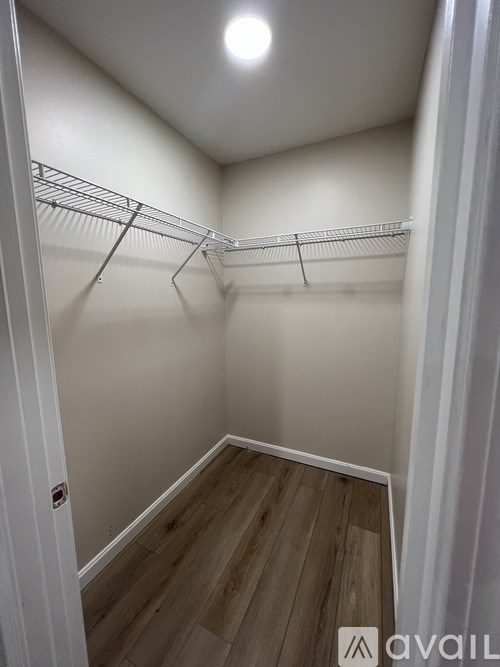 A walk-in closet with white walls and wood flooring.