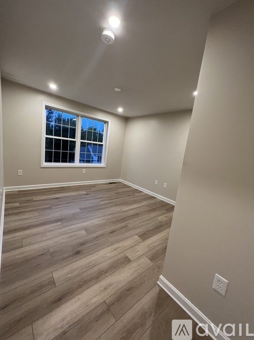 A room with a window and wooden flooring.