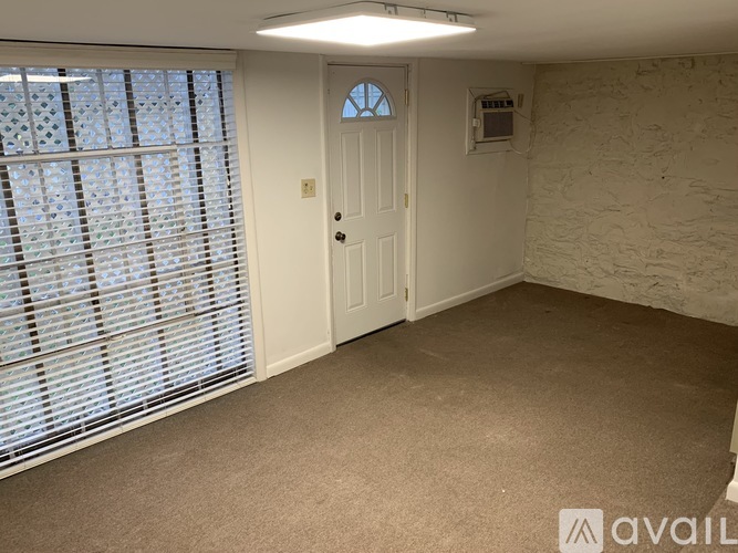 A room with a door, window with blinds, and a wall socket.