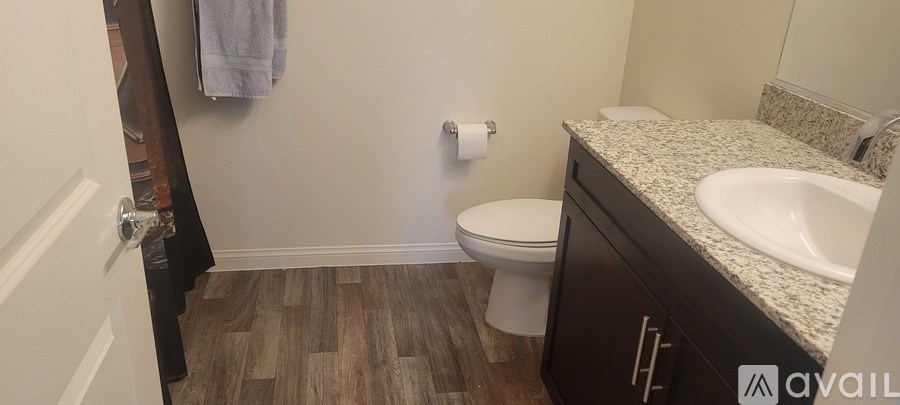 A bathroom with a toilet, sink, and a towel hanging on the wall.