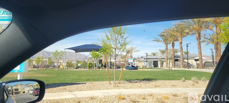 A car is parked in a lot with a blue umbrella and palm trees in the background.