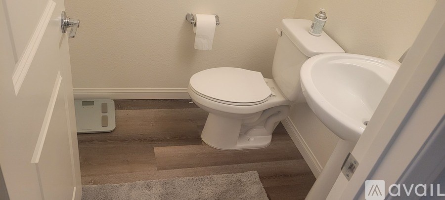 A white toilet in a small bathroom with a white tub and a white door.