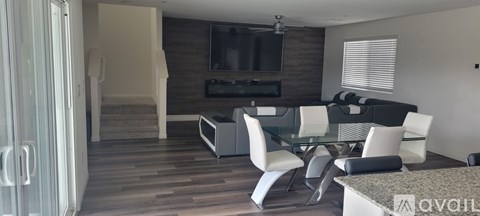 A modern living room with a glass table and white chairs.