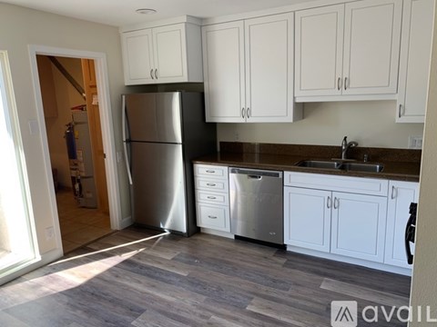 A kitchen with white cabinets and a black fridge.
