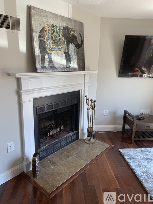 A large elephant painting is on the wall above a fireplace.