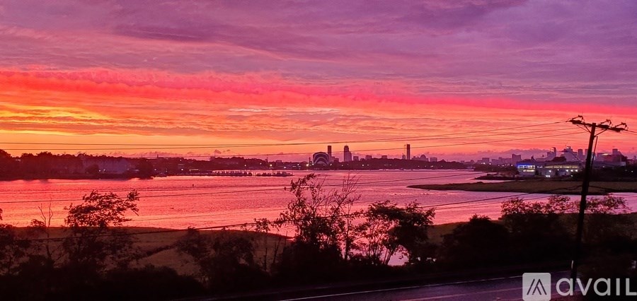 A sunset view of a city skyline with a body of water in the foreground.