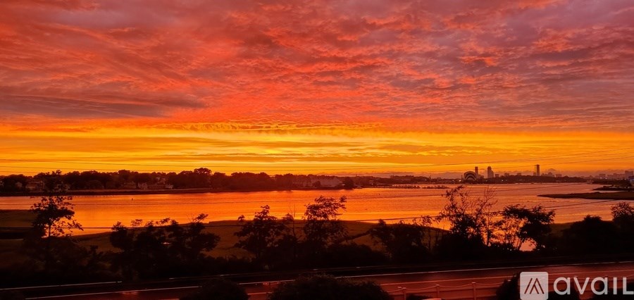 A beautiful sunset over a body of water with a city skyline in the distance.