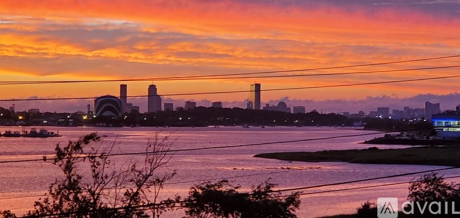 A city skyline is silhouetted against a sunset sky.