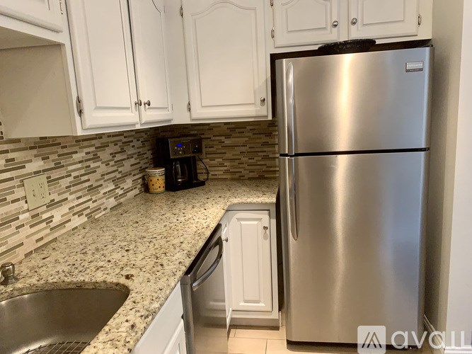 A kitchen with a stainless steel refrigerator and white cabinets.