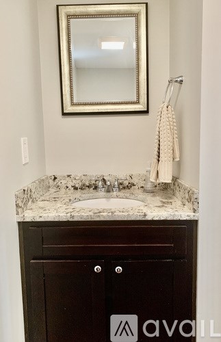 A bathroom with a marble counter top and a mirror above it.