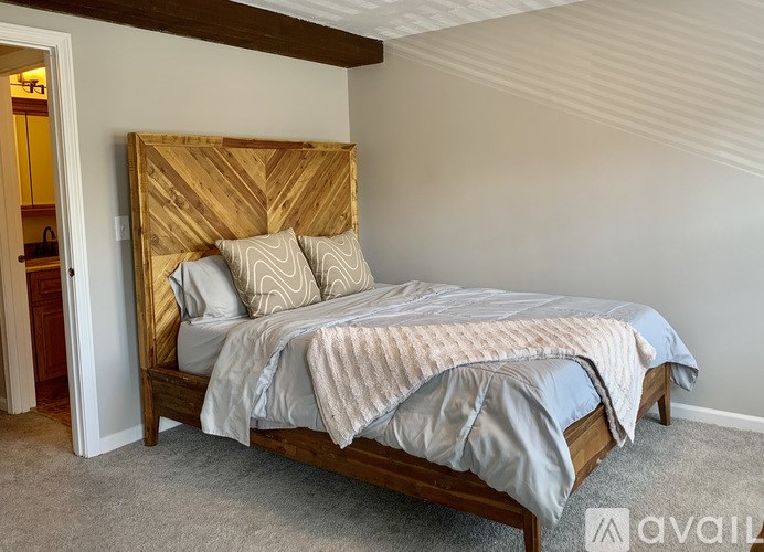 A bed with a wooden headboard and a grey comforter is in the image.