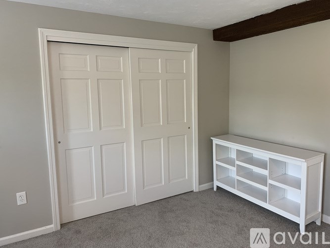 A room with a white door and a white shelf unit.