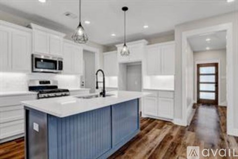 A modern kitchen with white cabinets and a blue island.