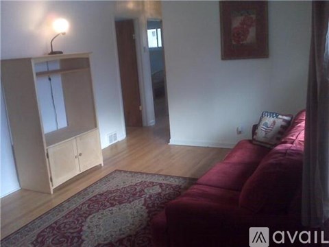 A living room with a red couch and a wooden cabinet.