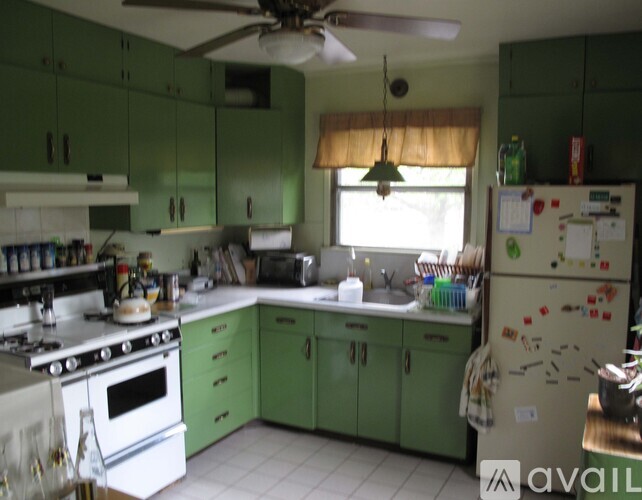 A kitchen with green cabinets and a white refrigerator.