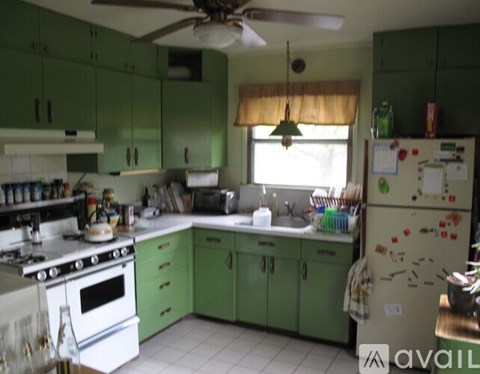 A kitchen with green cabinets and a white refrigerator.