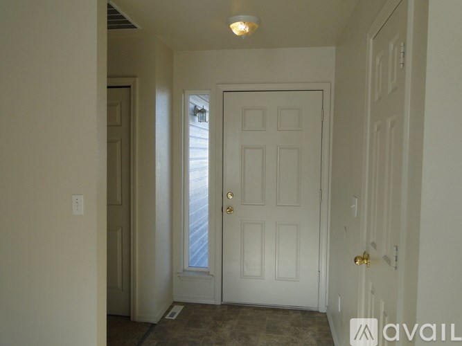 A white door with a gold handle is in the middle of a hallway.