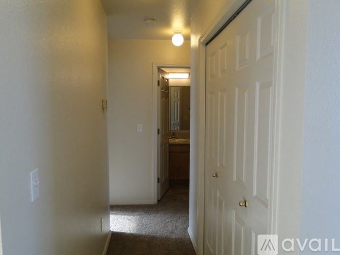 A hallway with a carpeted floor and white walls.