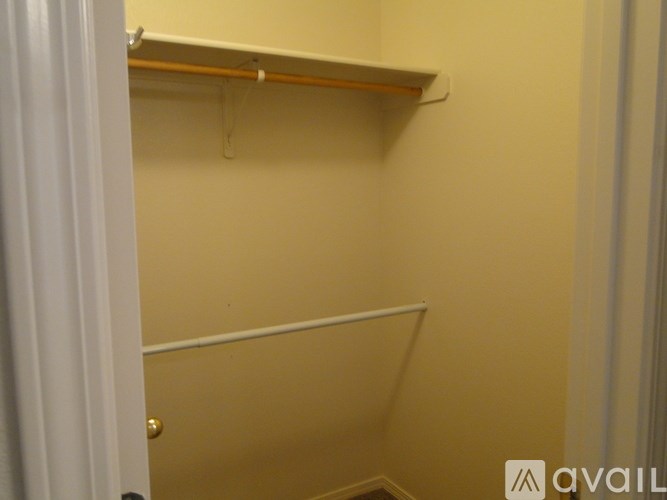 A white door is open to a small closet with a shelf and a white wall.