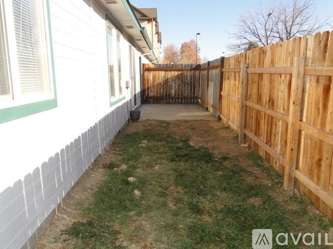 A backyard with a wooden fence and a white house.