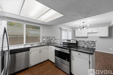 A kitchen with white cabinets and a black countertop.