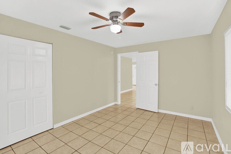 A room with a ceiling fan and tile flooring.