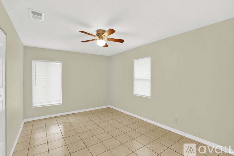 A room with a ceiling fan and two windows.