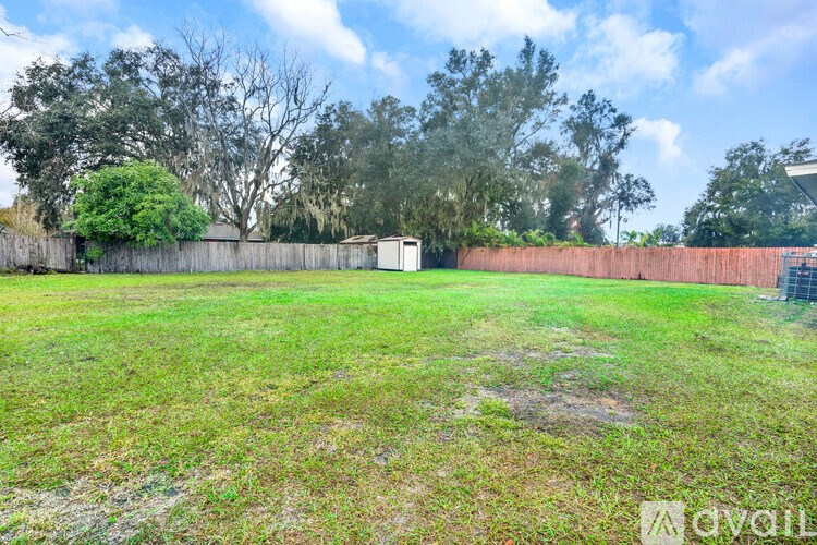 A grassy field with a fence and trees in the background.