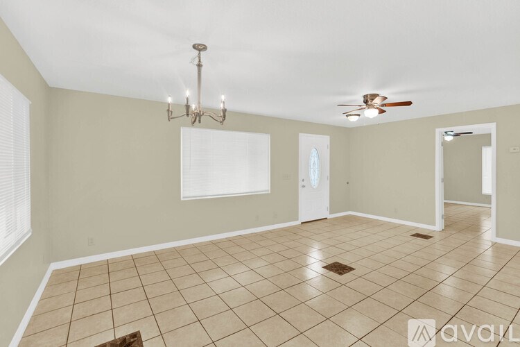 A room with a chandelier, ceiling fan, and tiled floor.