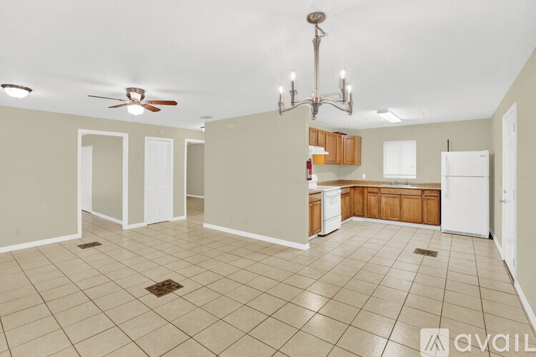 A spacious kitchen and living room with a chandelier and a ceiling fan.