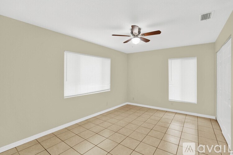 A room with a ceiling fan and two windows.