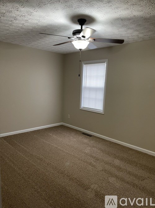 A room with a ceiling fan and carpeted floor.
