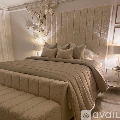 A bed with a white headboard and multiple pillows is in the foreground.
