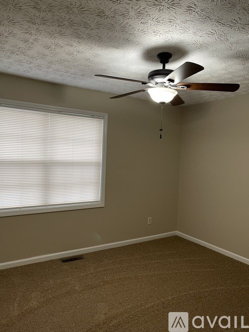 A room with a ceiling fan and a window with blinds.
