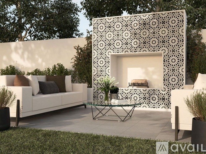 A white couch is placed in front of a white wall with a black and white pattern.
