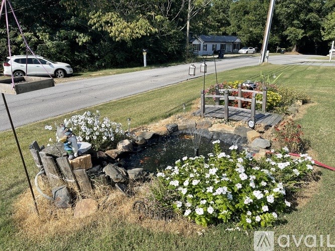 A garden with white flowers and a fire pit in the middle of a grassy area.