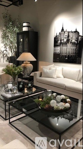 A black and white photo of a building is on the wall behind a white couch.