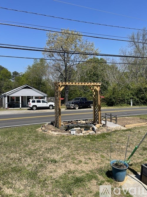 A garden with a wooden trellis and a white car in the background.