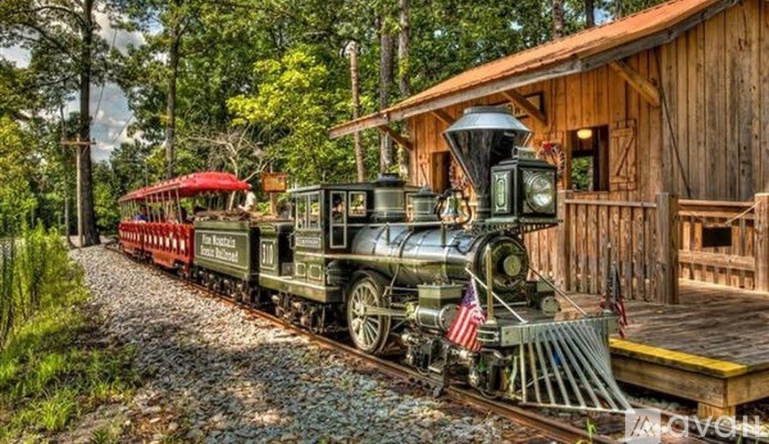 A steam engine train is on a track in front of a wooden building.