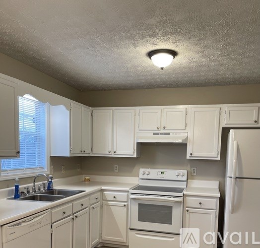 A kitchen with white cabinets and appliances.