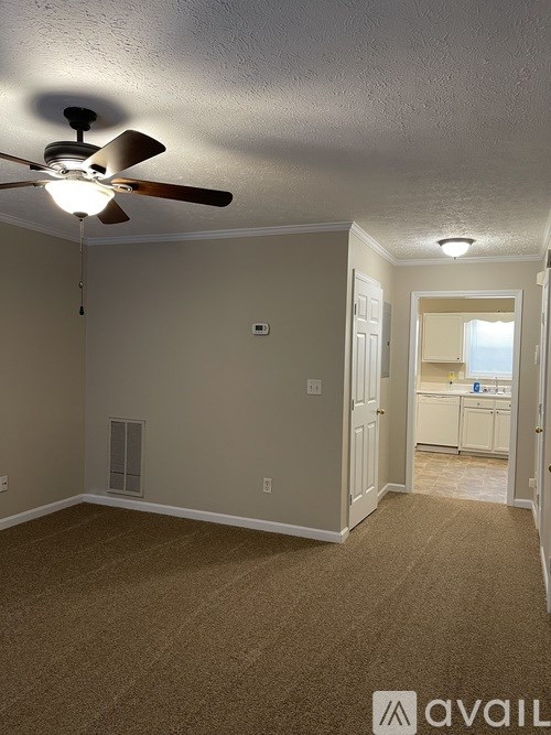 A room with a ceiling fan and carpeted floor.