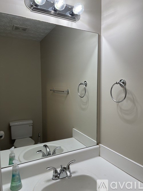 A bathroom with a toilet, sink, and mirror.